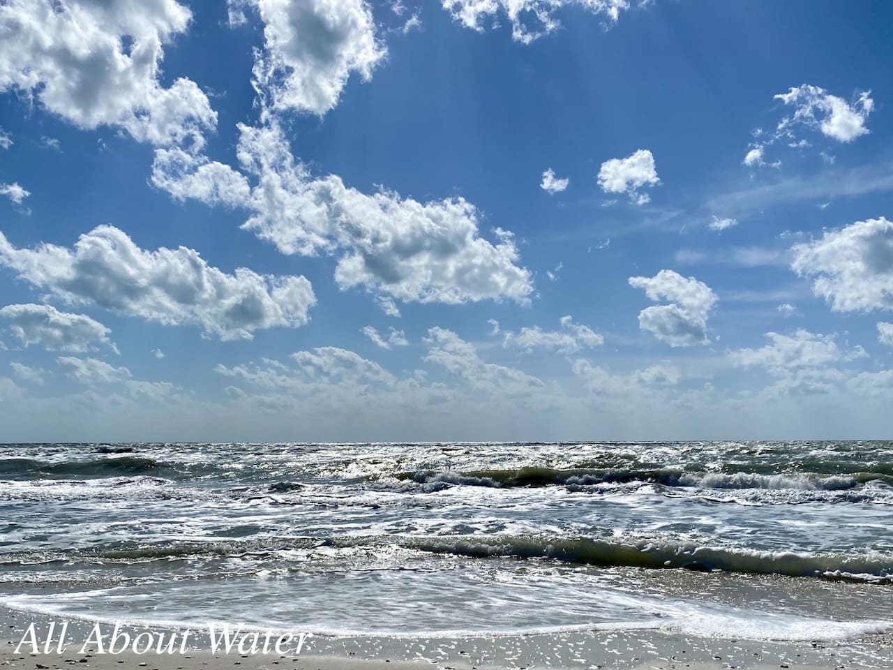 Blue sky, white clouds, and ocean waves.