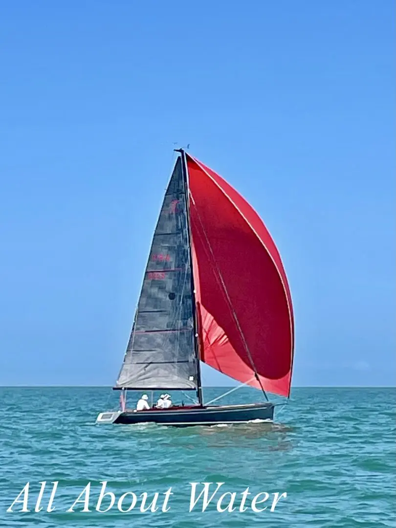 Sailboat with red sail on blue water.